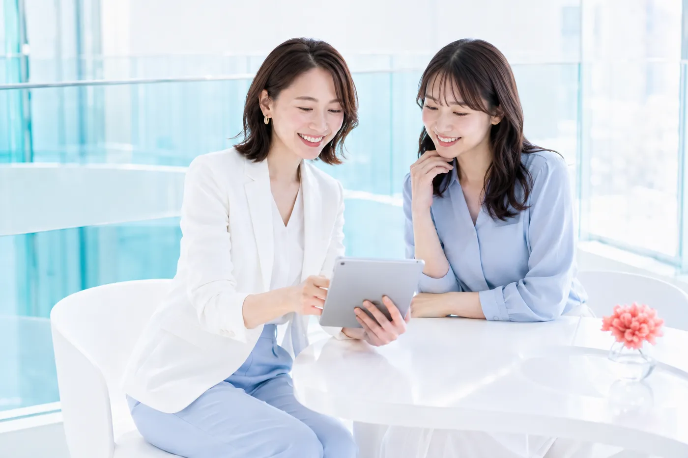 明るいスタジオでタブレットを見ながら相談する20代女性とカウンセラー